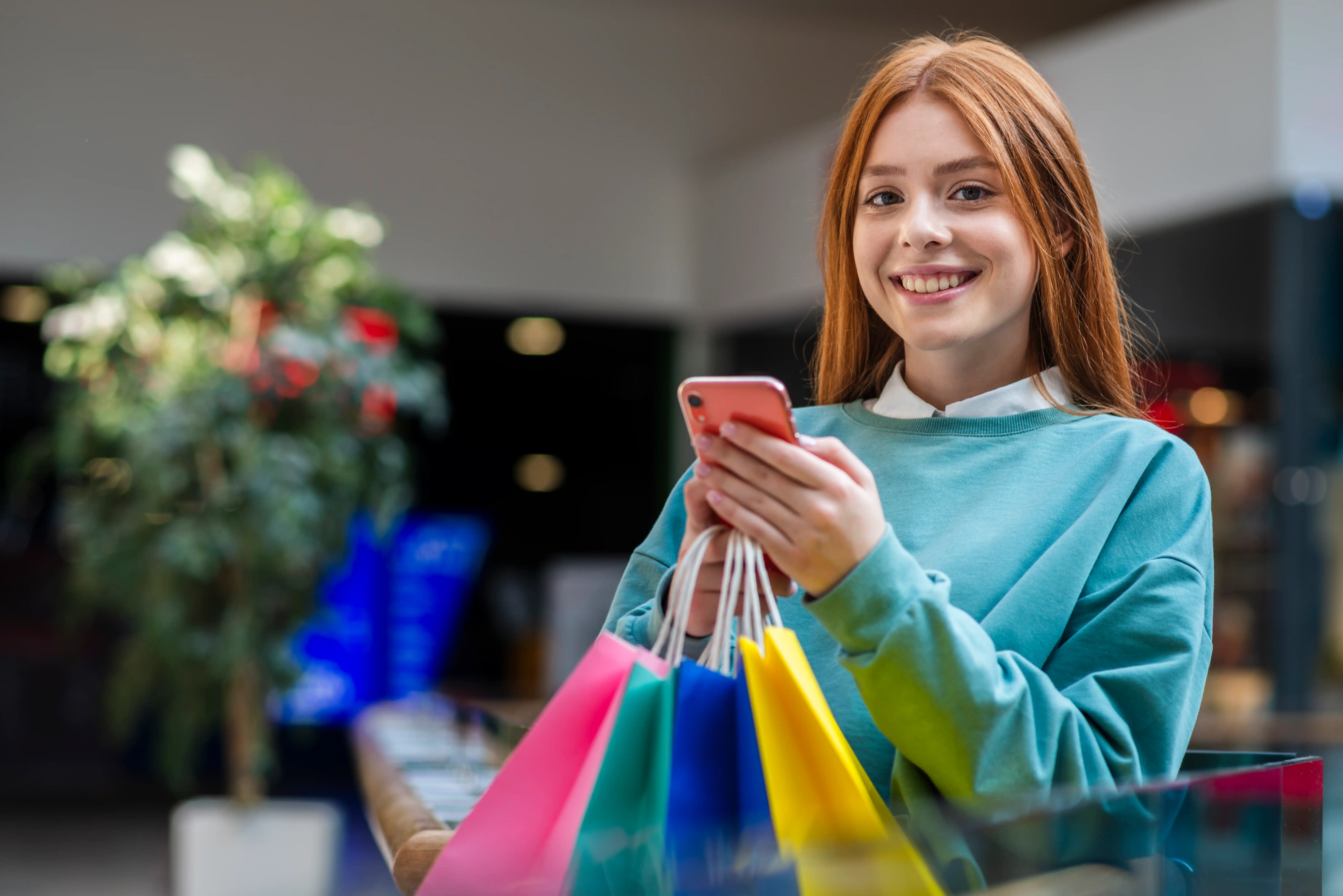 Smiling shopper with colourful shopping bags, ordering on her phone from OzGalore